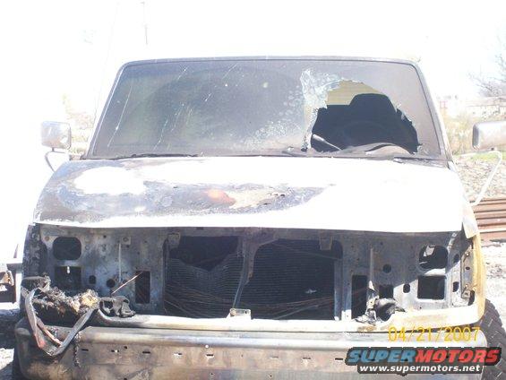 front of burnt van, windshield broken, grille missing, front end damaged