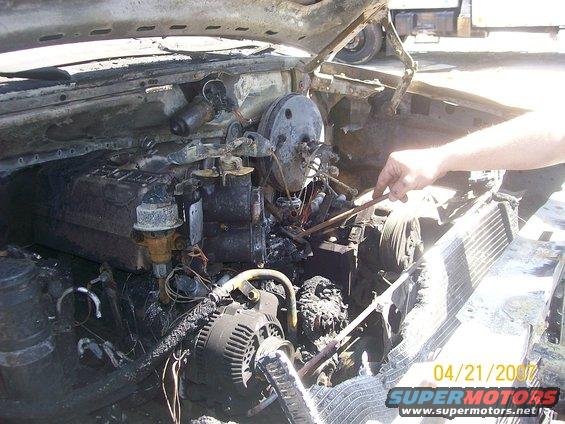 Burnt engine compartment with visible alternator, radiator, and brake booster
