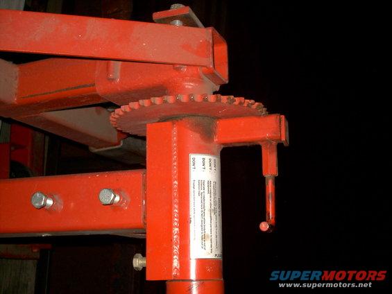 Red metal jack stand with a toothed gear and a warning label