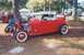 2002 Ford Crown Victoria - A red hot rod roadster is parked outdoors with other vehicles and people in the background.
