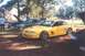 2002 Ford Crown Victoria - A yellow Ford Mustang is parked next to a dark green car with its hood open.