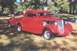2002 Ford Crown Victoria - A bright red hot rod coupe with a custom bed and exposed engine sits on a grassy field.