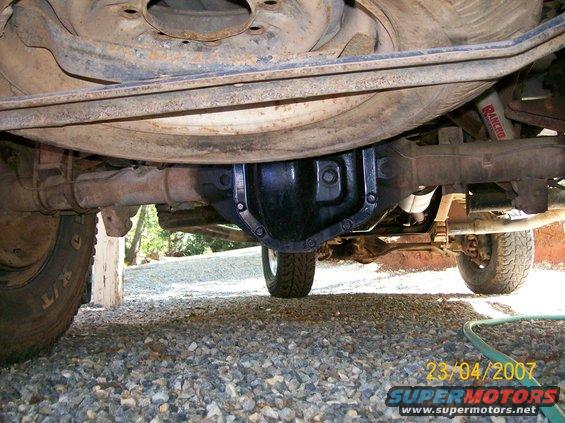 Underside view of a vehicle's rear axle, differential, and suspension components. Rancho shock absorber visible