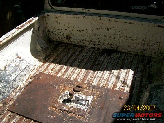 White truck bed interior with ribbed floor and rusty metal plate