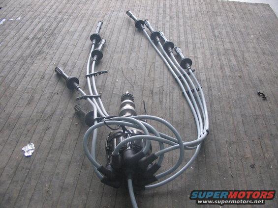 Ford distributor with spark plug wires laid out on a wooden floor