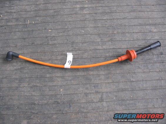 Orange spark plug wire with black and red boots on wooden planks