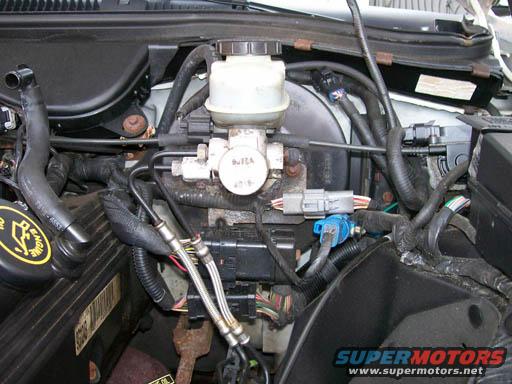 Engine bay with brake fluid reservoir, master cylinder, and wiring harnesses. A yellow "ENGINE OIL" cap is visible