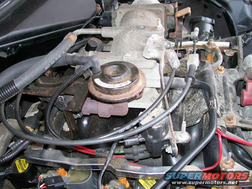 Engine bay with hoses, wires, and a valve. Text reads "SUPERMOTORS.NET"