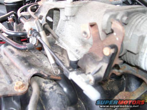 Close-up of engine throttle linkage with rusty metal parts and cables