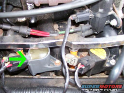 Engine ignition coils and wiring with a green arrow pointing to one coil