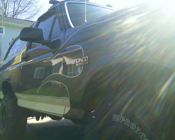 Dark green Ford Bronco with white pinstriping and a white stripe along the lower body, seen from the front quarter angle