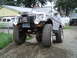 1989 Ford Bronco - Silver Suzuki Samurai equipped with a winch and large off-road tires is parked on a gravel incline. A second vehicle is visible in the back…