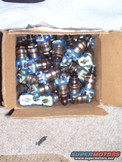 Cardboard box filled with numerous blue and black fuel injectors