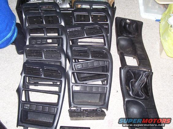 Black dashboard trim pieces and center console parts laid out on a floor