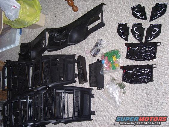Car dashboard parts and instrument clusters laid out on carpet