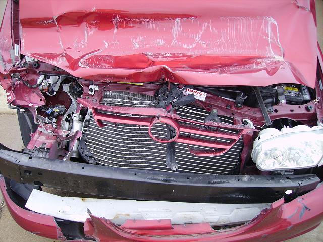 Damaged red car front end showing crumpled hood, bent grille, and exposed radiator