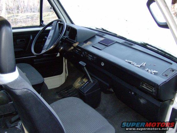 Van interior showing dashboard, steering wheel, and seats. Small parts are scattered on the dashboard