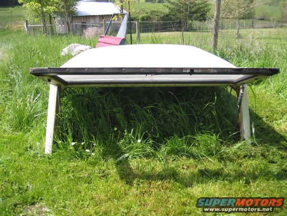 White hardtop propped up on supports in tall grass