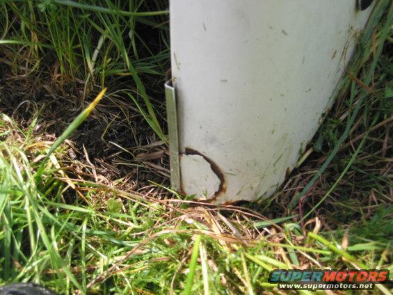 White vehicle fender with rust damage and a metal bracket