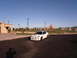 1996 Ford Probe - A white Dodge Neon SRT-4 is parked in a lot with buildings and mountains in the background.