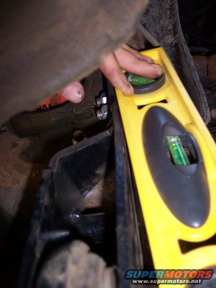 Yellow level tool with green bubble vials used on black metal bracket and bolts