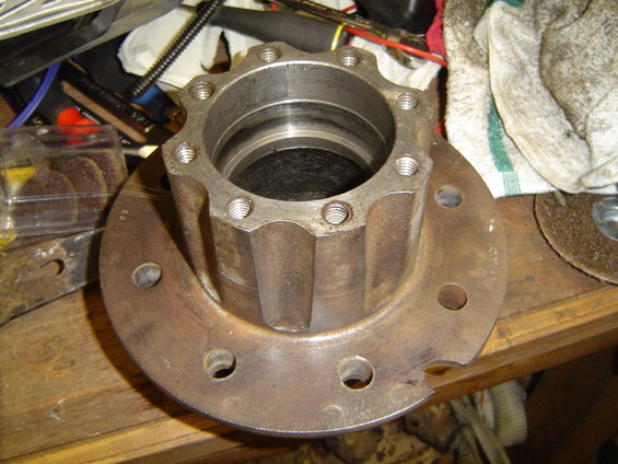 Close-up of a Dana 70 FF axle hub with 10 bolt holes on a wooden surface, surrounded by tools