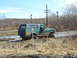1996 Ford Bronco - A green Ford Bronco navigates a muddy terrain near railroad tracks under a bright sky.