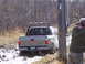 1996 Ford Bronco - A tan pickup truck navigates a muddy off-road trail, kicking up dirt as it goes.