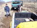 1996 Ford Bronco - Two trucks are stuck in the mud with two people attempting to free one of them.