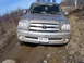 1996 Ford Bronco - A muddy Toyota Tundra navigates off-road terrain, its front grille and V8 emblem clearly visible.