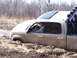 1996 Ford Bronco - A driver navigates a tan pickup truck through a muddy off-road trail, getting stuck in the mire.