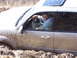 1996 Ford Bronco - Toyota Tundra stuck in mud with driver smiling.