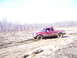 1996 Ford Bronco - Red Ford Ranger stuck in mud, driver visible inside.