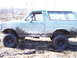 1996 Ford Bronco - A heavily muddied 1992 Ford Bronco is shown from the side, navigating a wet, grassy area.