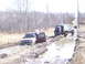 1996 Ford Bronco - Two trucks are stuck in the mud on an off-road trail, with people attempting to free them.