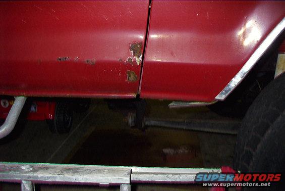 1979 Ford F-150 red door bottom showing rust and chrome trim