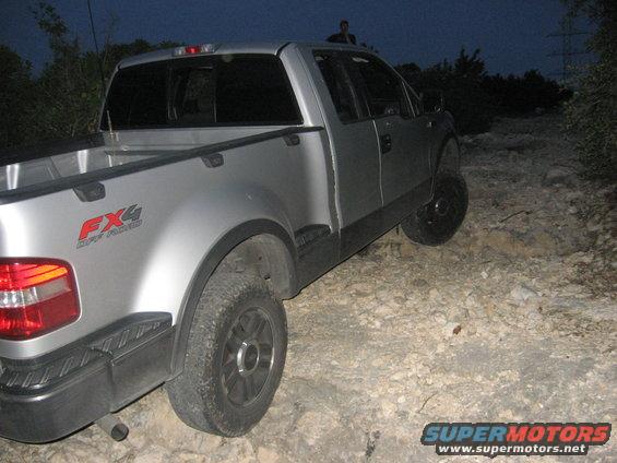 Silver pickup truck with FX4 off-road badging on the rear fender, parked on a rocky trail at dusk