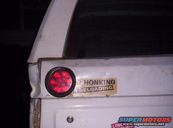 White SUV tailgate with a round red LED taillight and a "HONKING / RELOADING" sticker