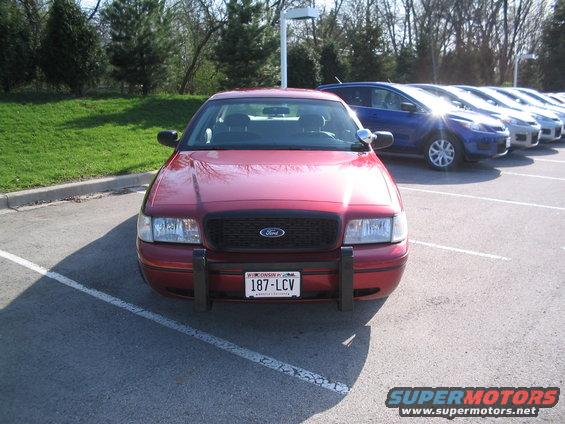 Red 2001 Ford Crown Victoria with a black grille and push bar, parked in a lot
