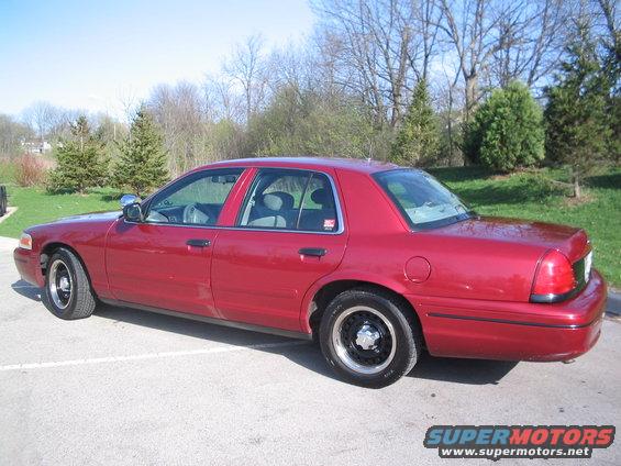 Red 2001 Ford Crown Victoria sedan parked on asphalt, side view