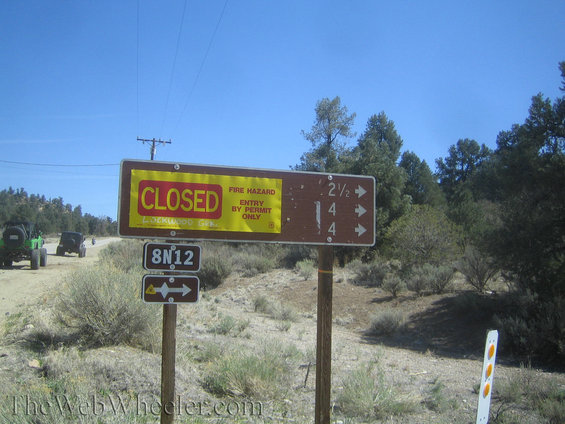 Two off-road vehicles on a dirt road near a closed sign