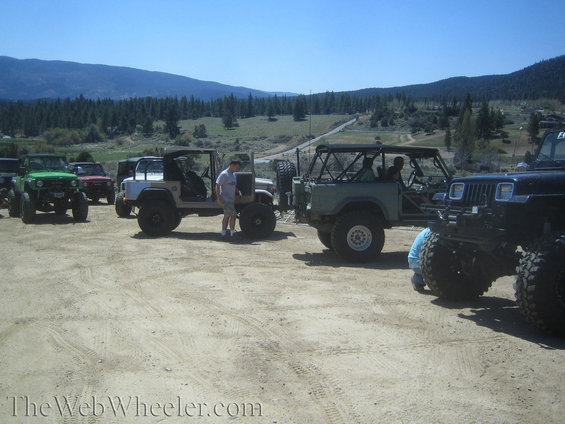 Several off-road vehicles parked in a dirt lot