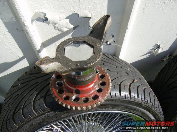 Tire with a wire wheel, red wheel hub, and a lug wrench tool on top