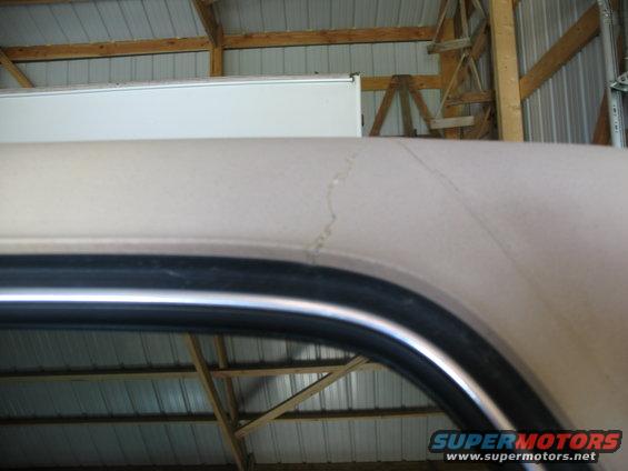 Tan vehicle roofline with a crack in the paint, viewed from inside a garage