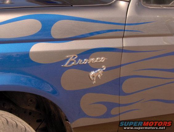 Silver Ford Bronco fender with blue flame graphics and a chrome Bronco emblem