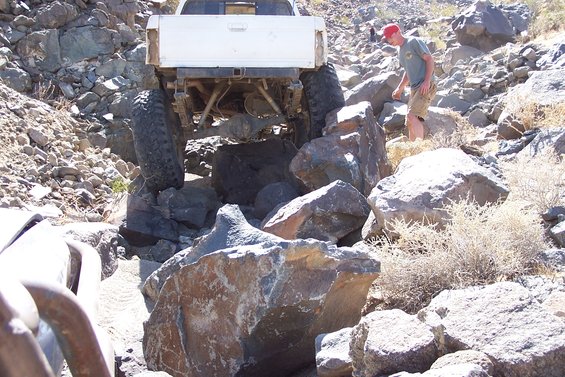 White pickup truck with large tires navigating a rocky trail