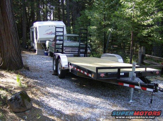 green pickup truck towing a trailer with a camper