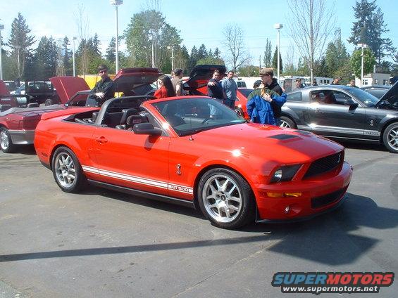 Red convertible sports car with white racing stripes and GT500 badging