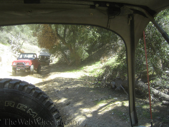 Red off-road vehicle on a dirt trail with another vehicle behind it