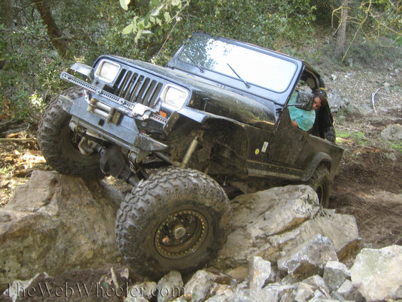 Black Jeep Wrangler navigating a rocky trail, front passenger side visible